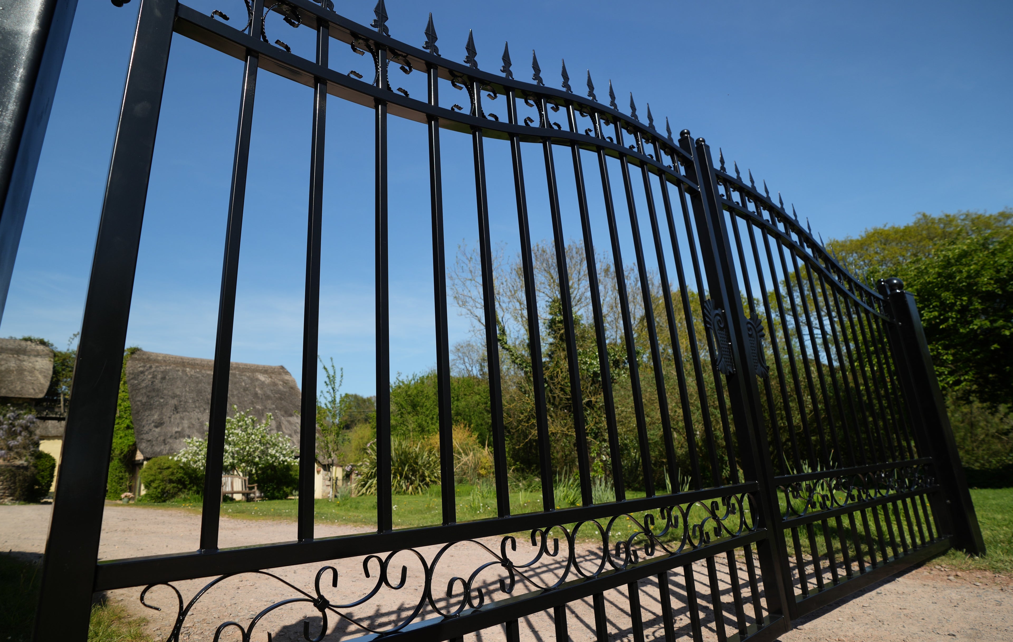 Wrought iron gate with a scenic background of trees and buildings.